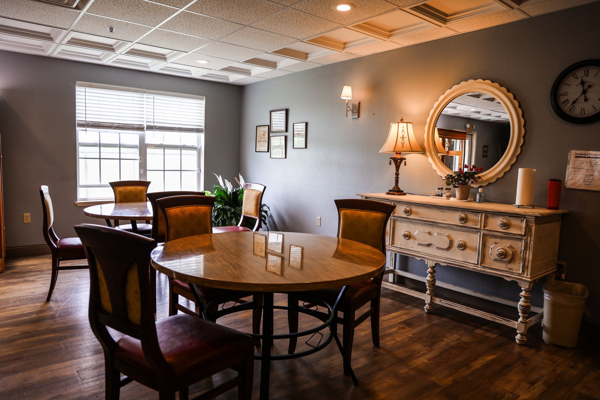 A dining room with tables and chairs and a clock on the wall.