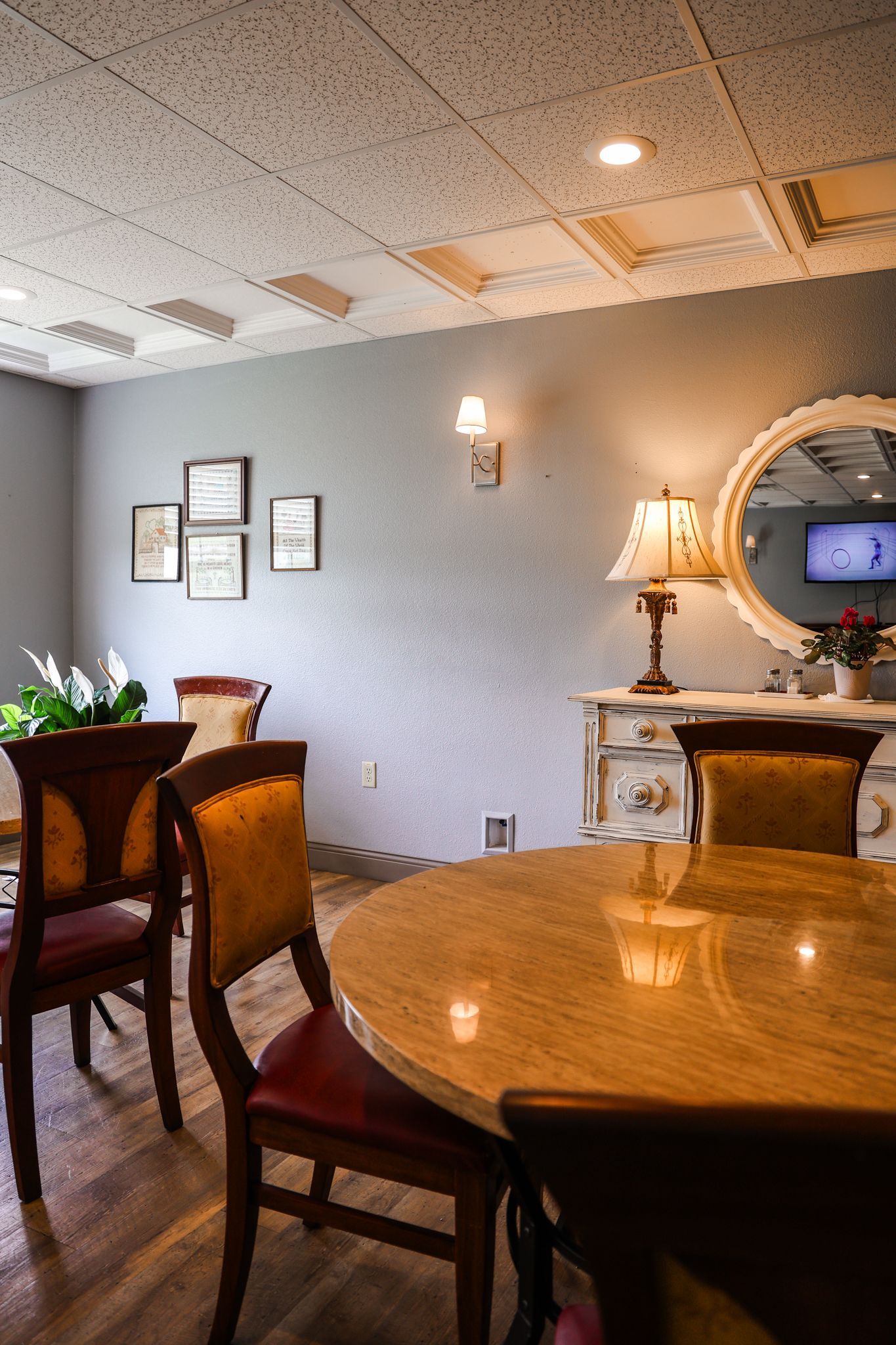 A dining room with a table and chairs and a mirror.