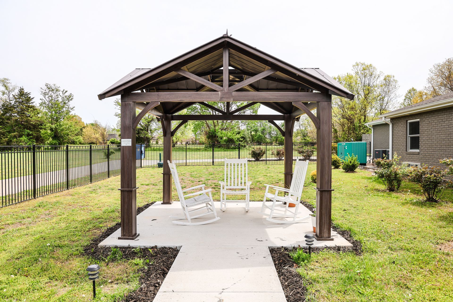 A gazebo with rocking chairs underneath it in a yard.