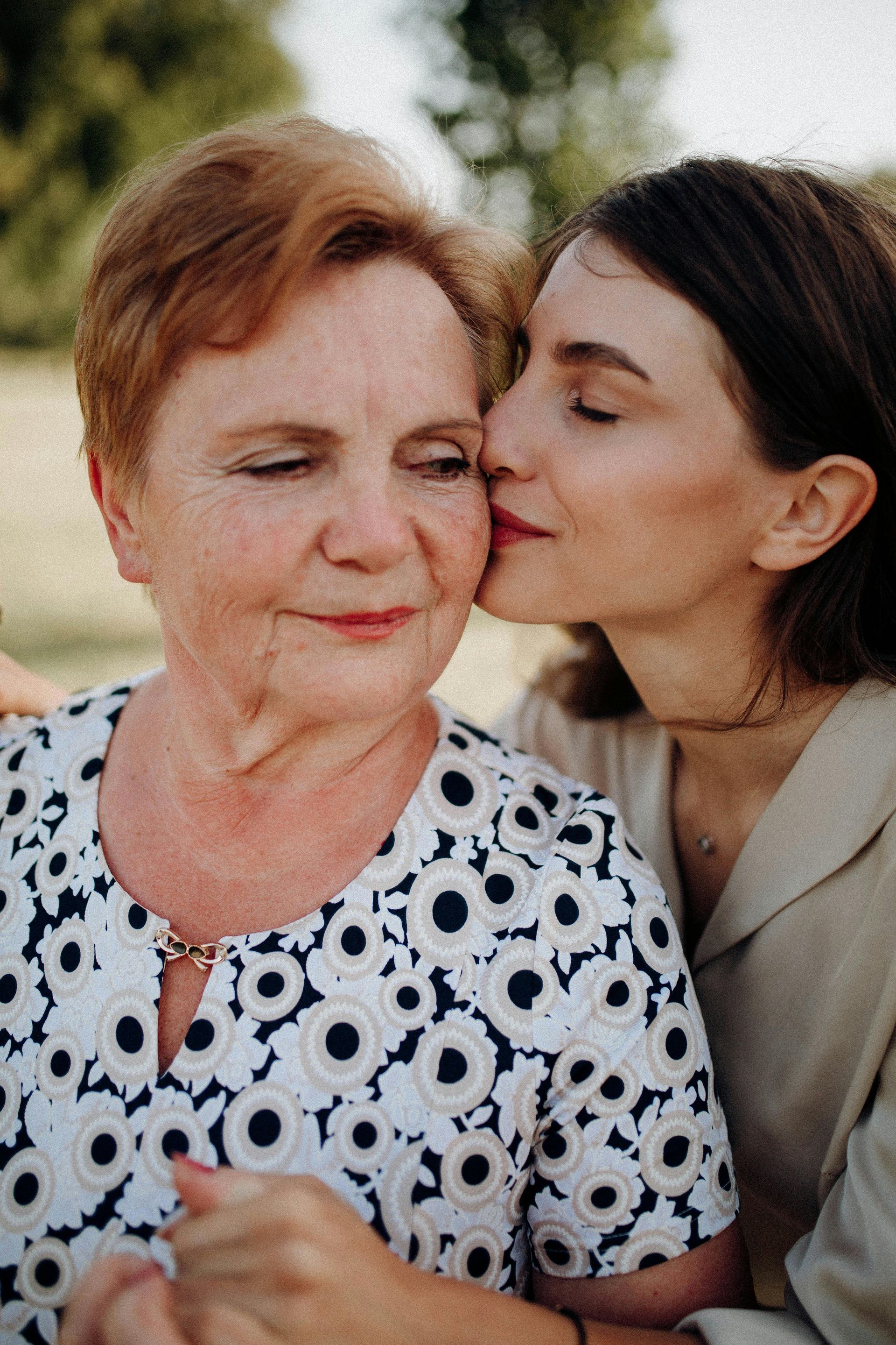 A woman is kissing an older woman on the cheek.