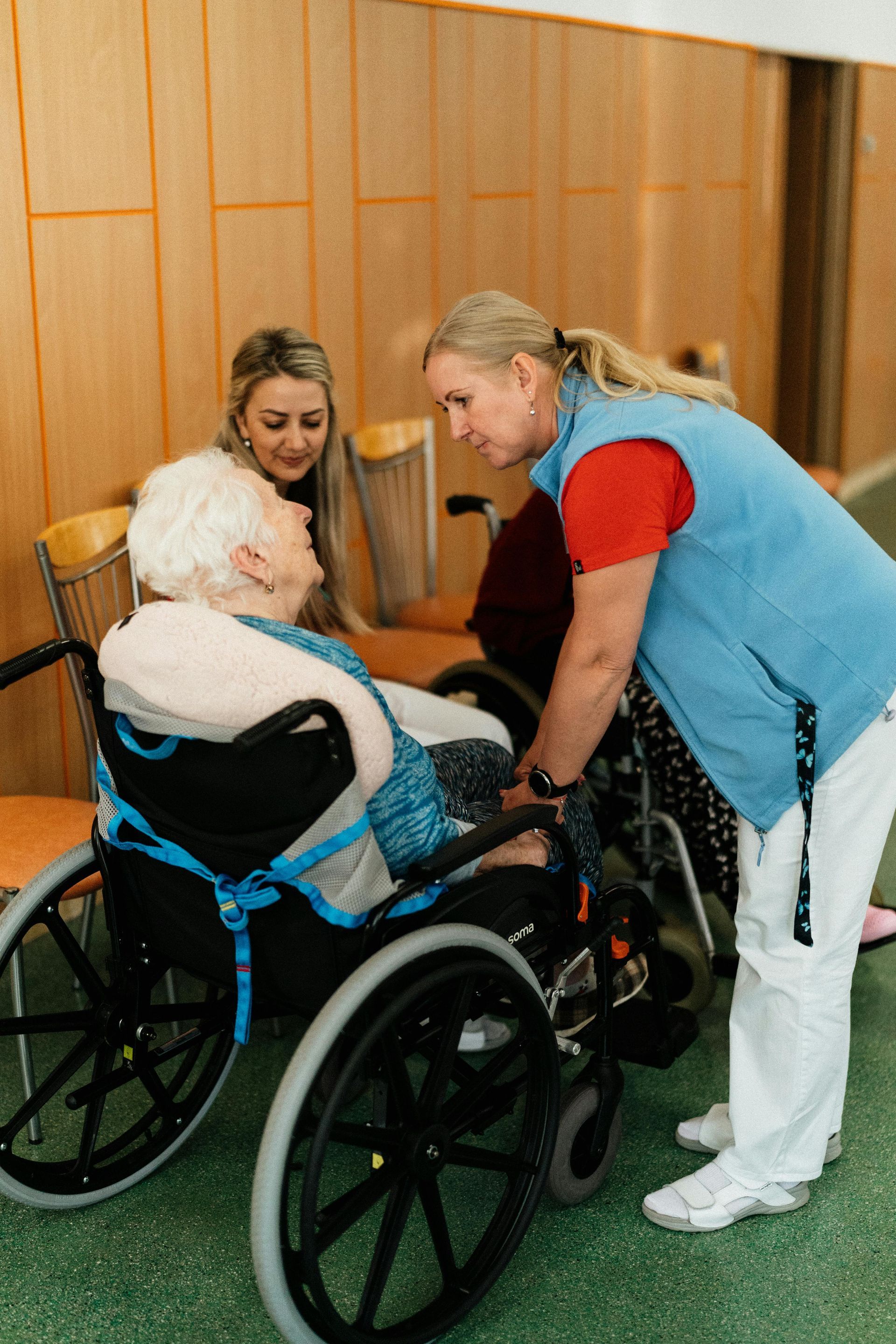 An elderly woman in a wheelchair is being helped by a nurse | Best assisted living near springfield mo