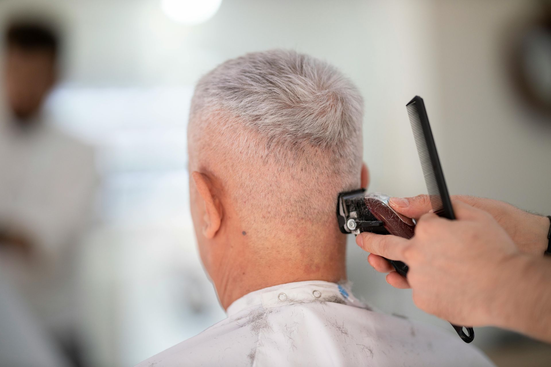 A man is getting his hair cut by a barber.