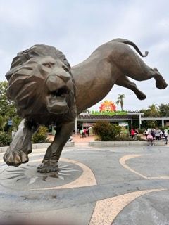 A statue of a lion and a panther in front of a zoo entrance.