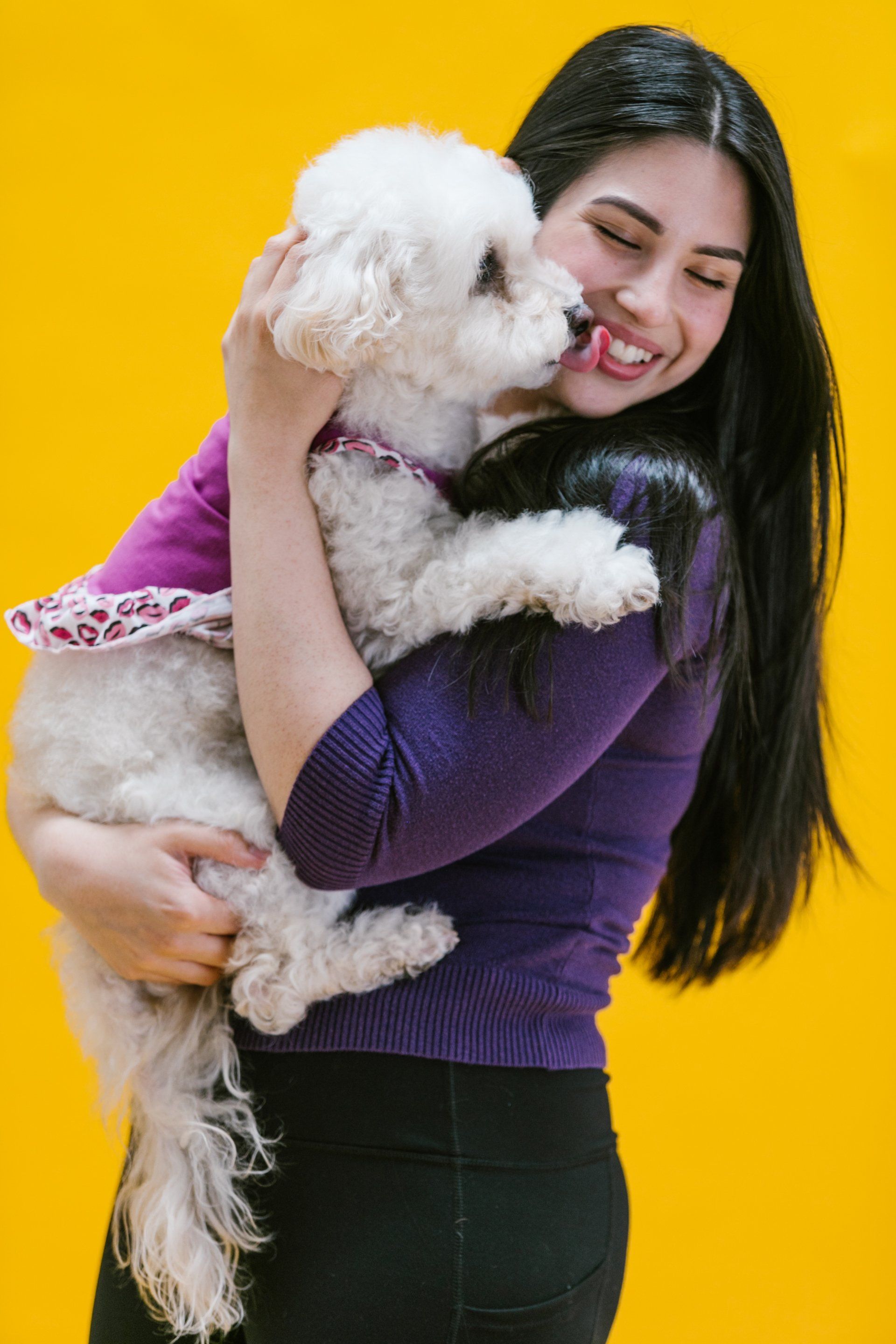 Woman happily holding a white dog smiling and happy