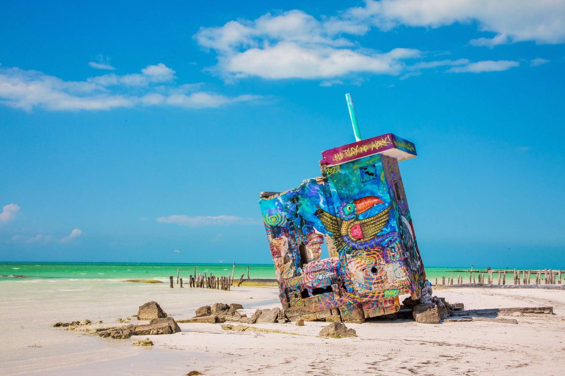 A colorful building is sitting on top of a sandy beach next to the ocean.