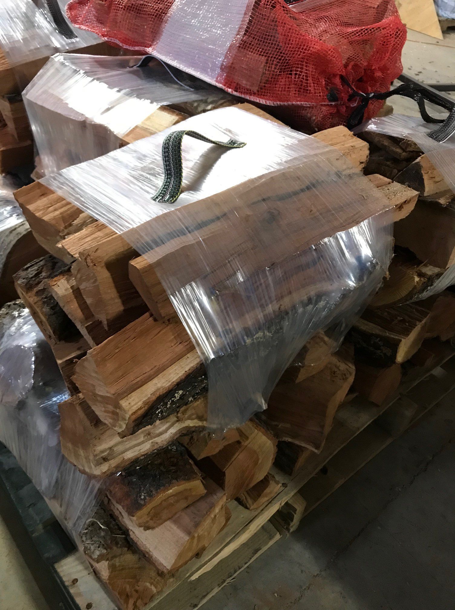 A pile of wood is wrapped in plastic and sitting on top of a pallet.