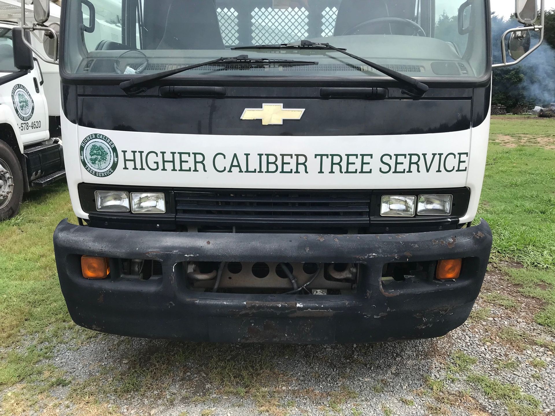 A higher caliber tree service truck is parked in a gravel lot.