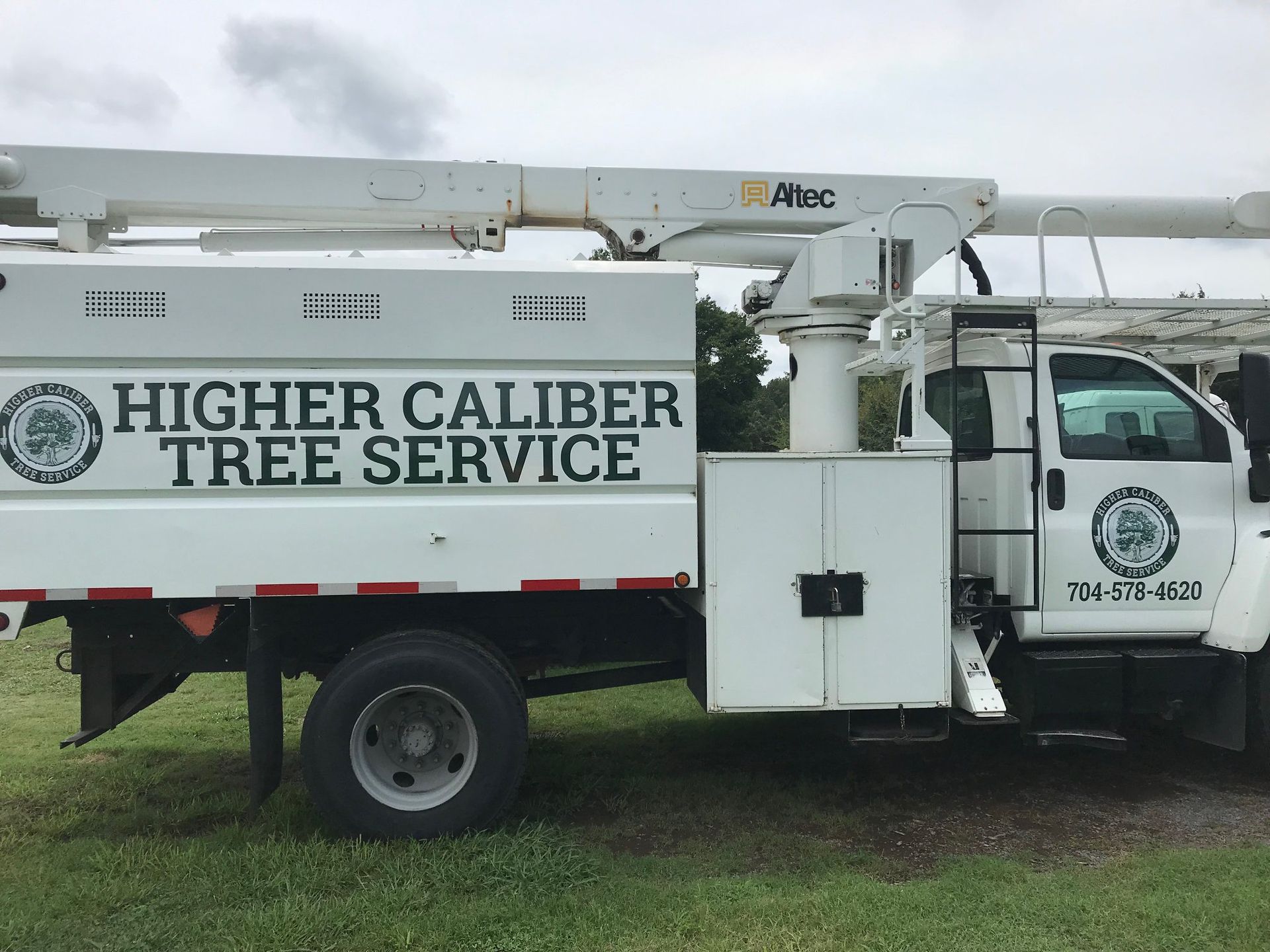 A higher caliber tree service truck is parked in a grassy field