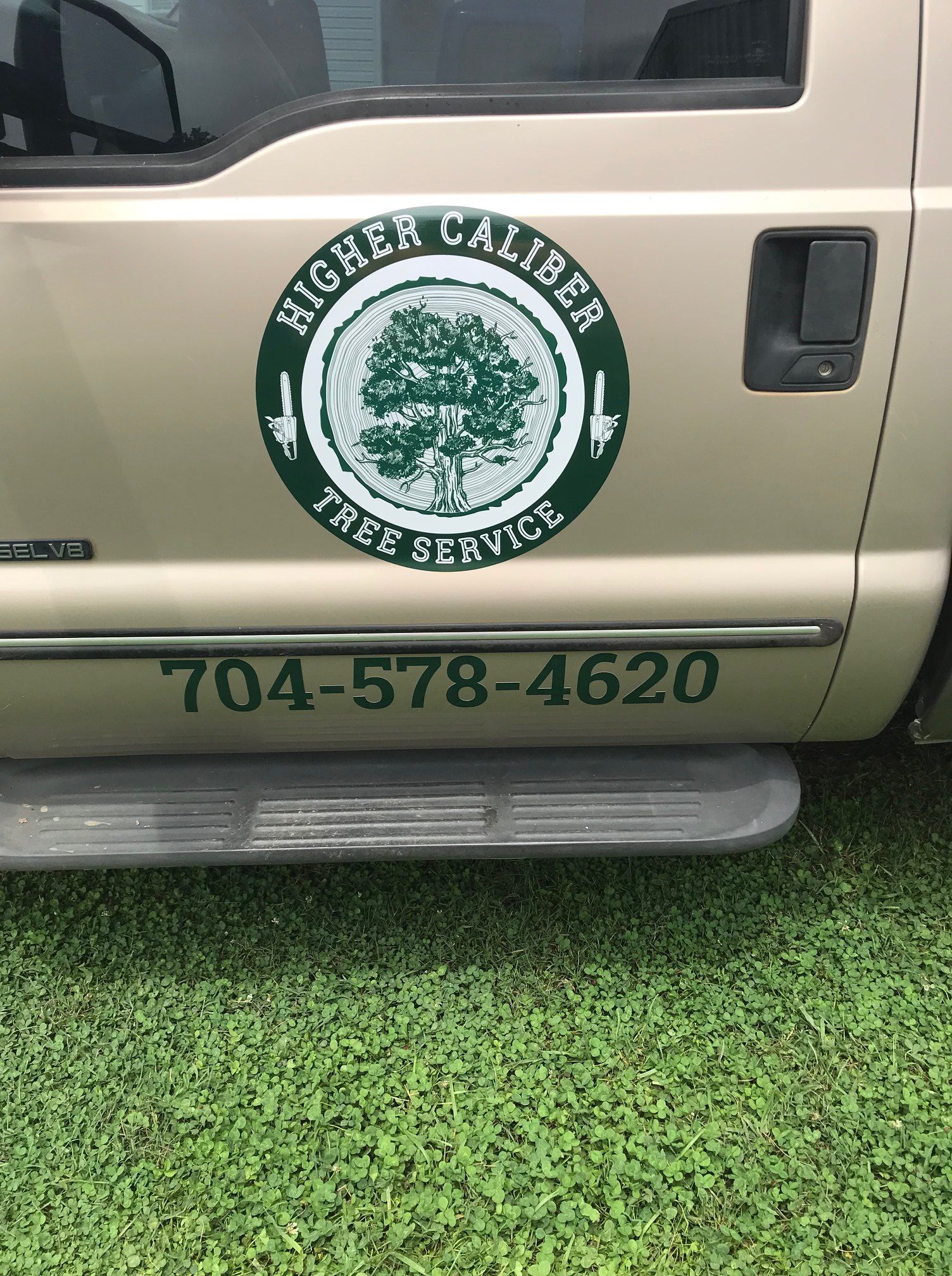 A higher caliber tree service truck is parked in the grass.