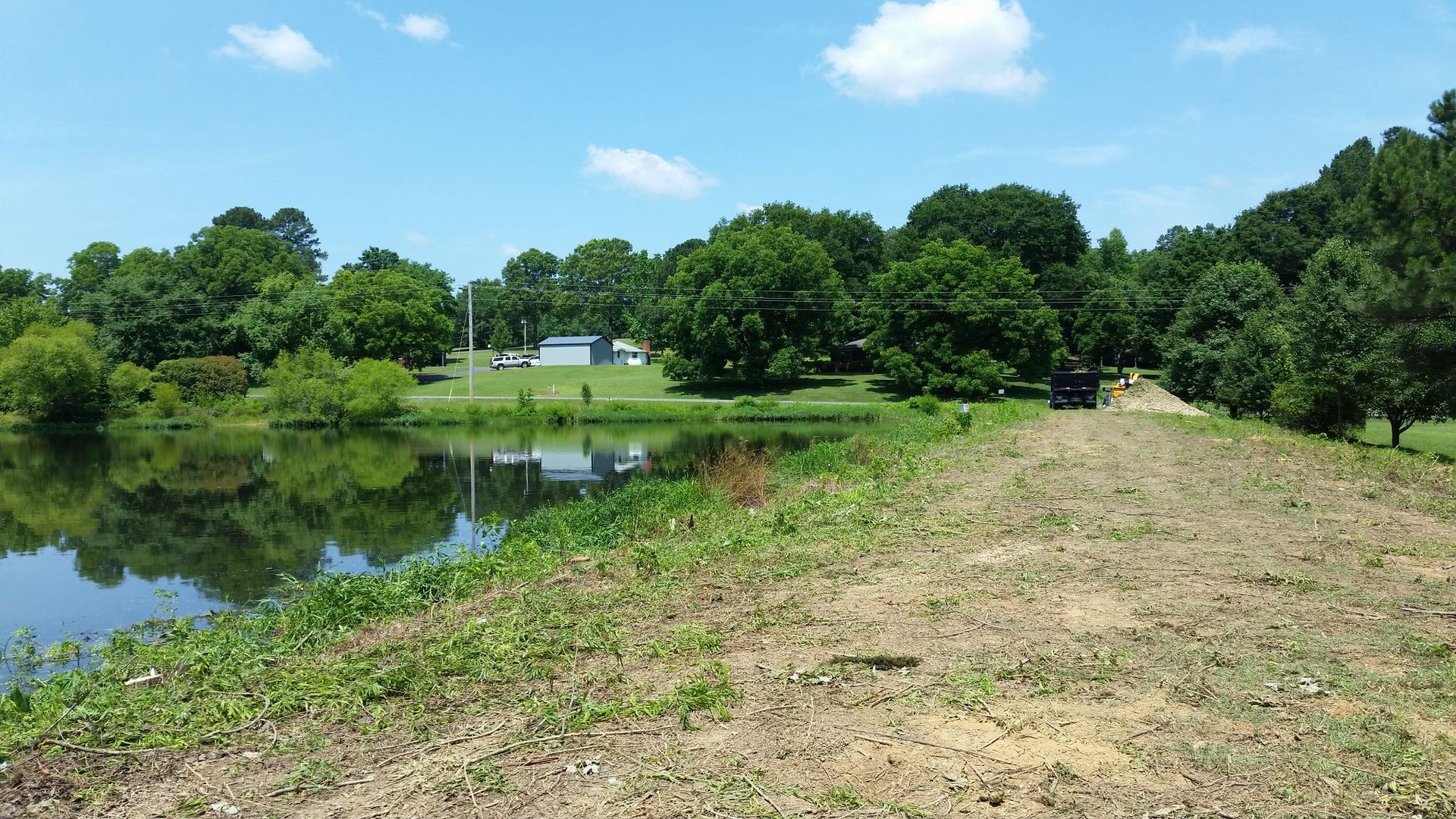 A lake surrounded by trees and grass on a sunny day