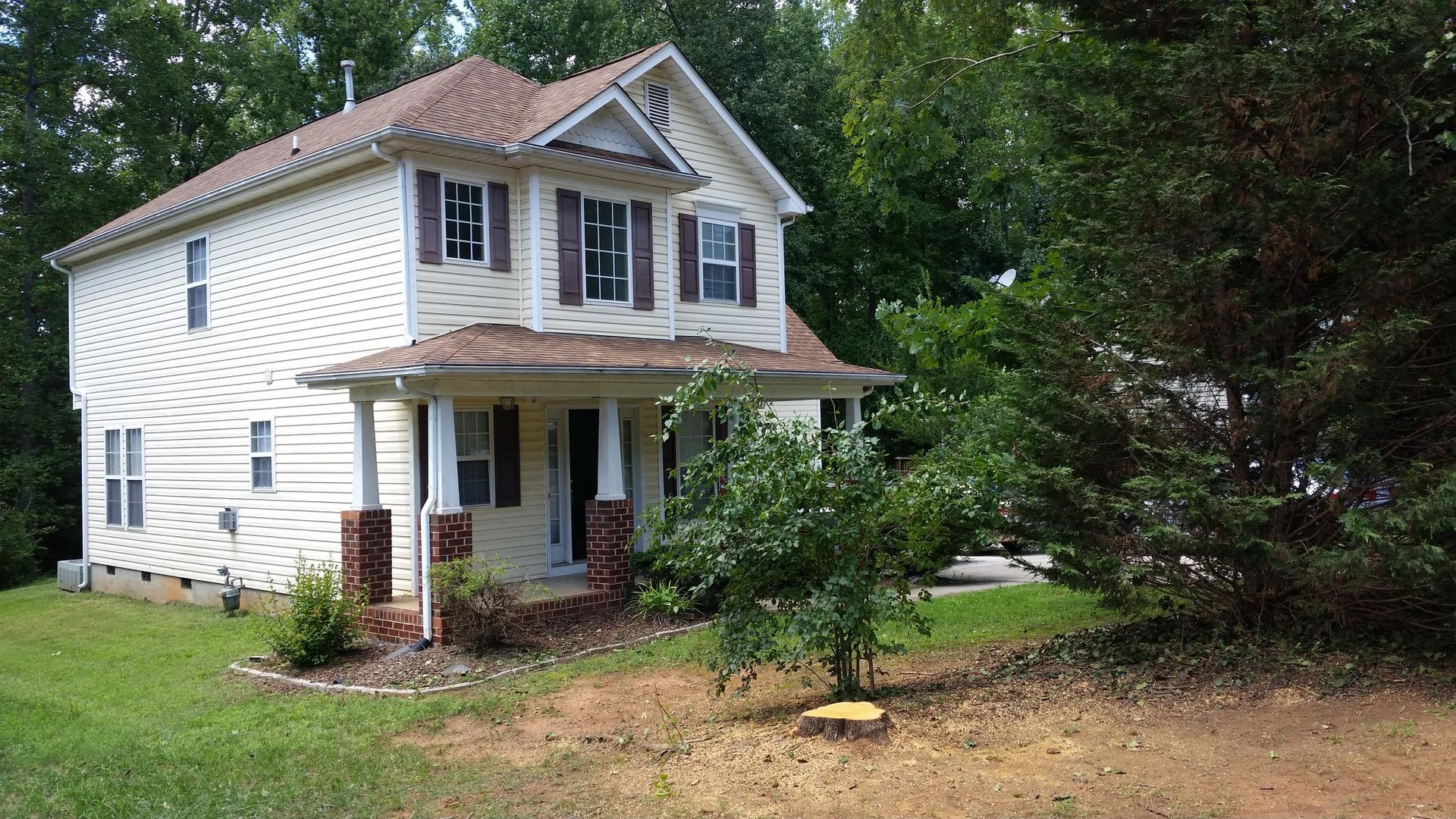 A white house with a brown roof is surrounded by trees.