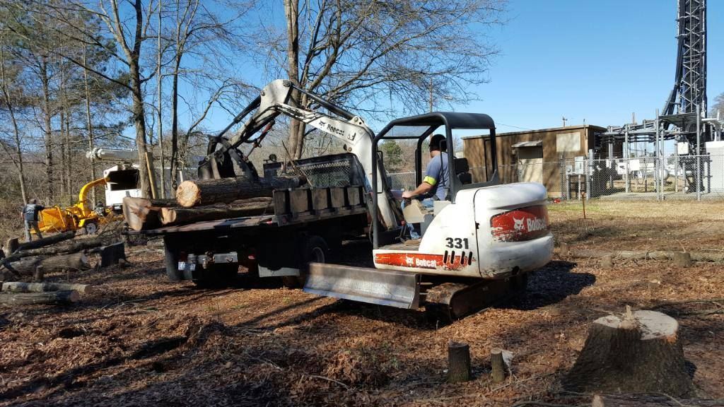 A man is driving a small excavator in a field.