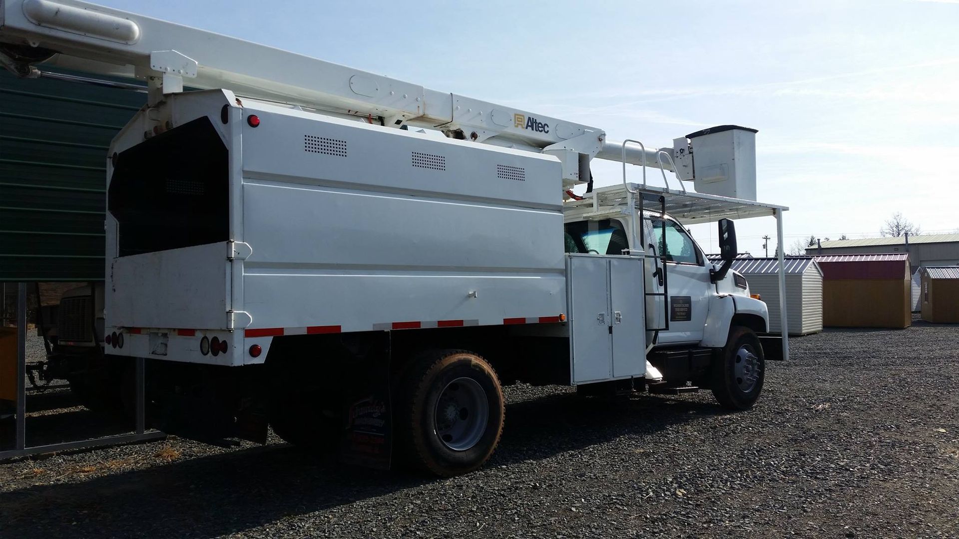 A white utility truck is parked in a gravel lot.