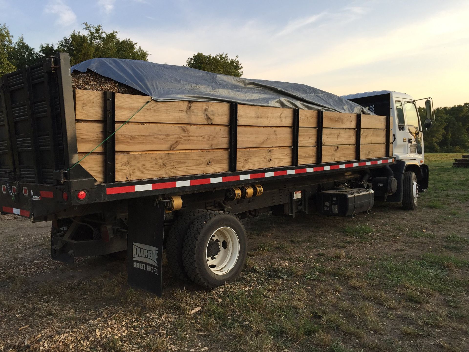 A truck with a wooden bed is parked in a field.