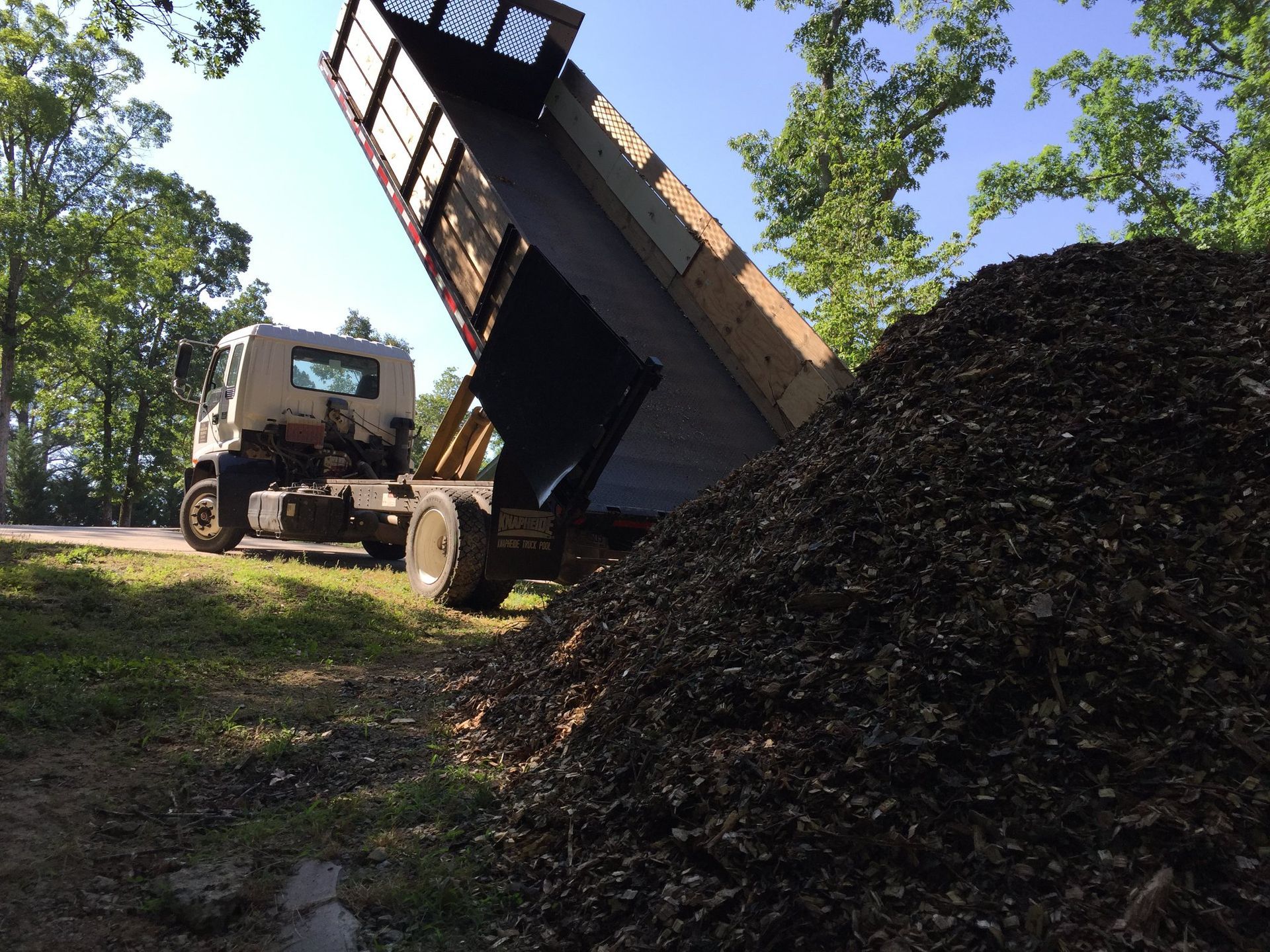 A dump truck is dumping a large pile of dirt