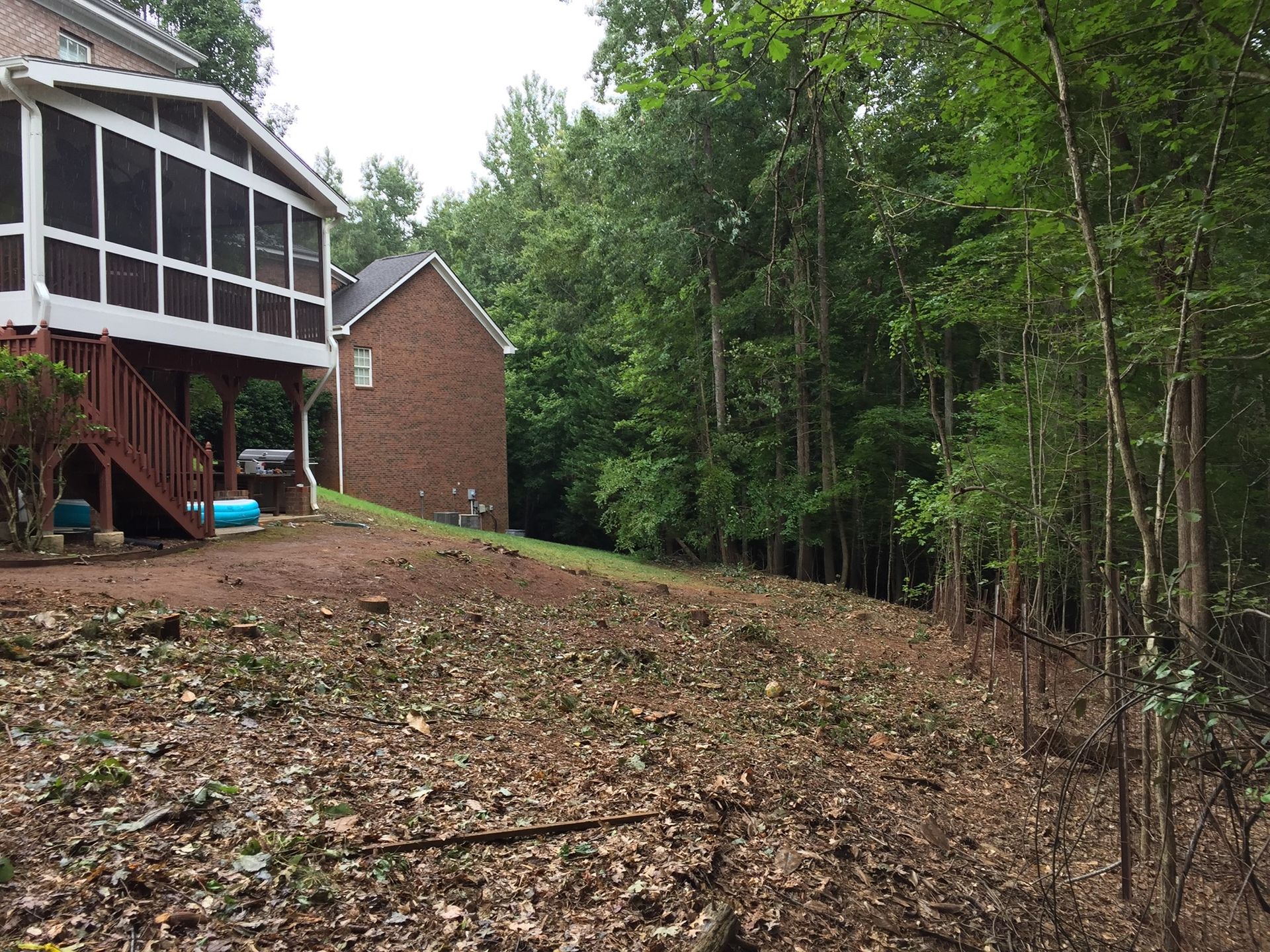 A brick house with a screened in porch is surrounded by trees.