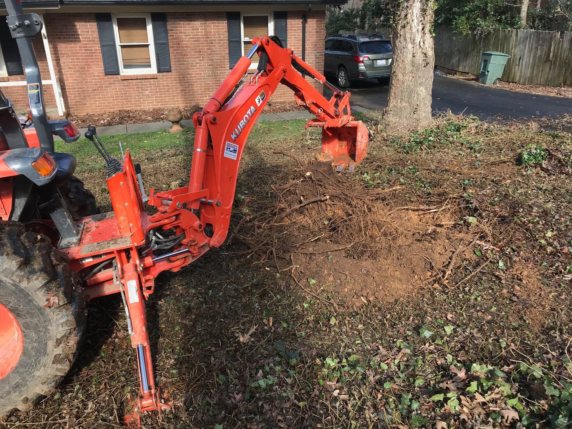 A tractor with a backhoe attached to it is parked in front of a house.