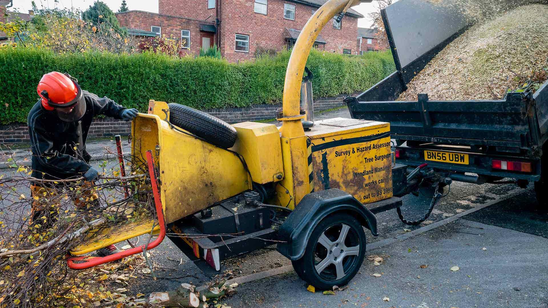 A man is working on a tree chipper on a trailer.