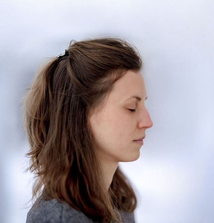 Seitliches Profil einer Frau mit geschlossenen Augen beim Meditieren.