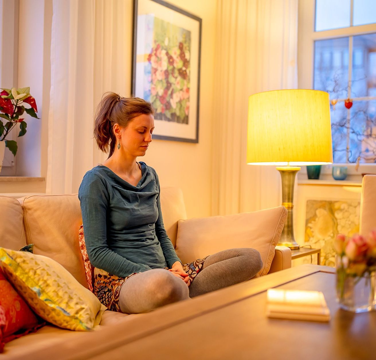 Frau meditiert einfach und bequem zuhause auf dem Sofa