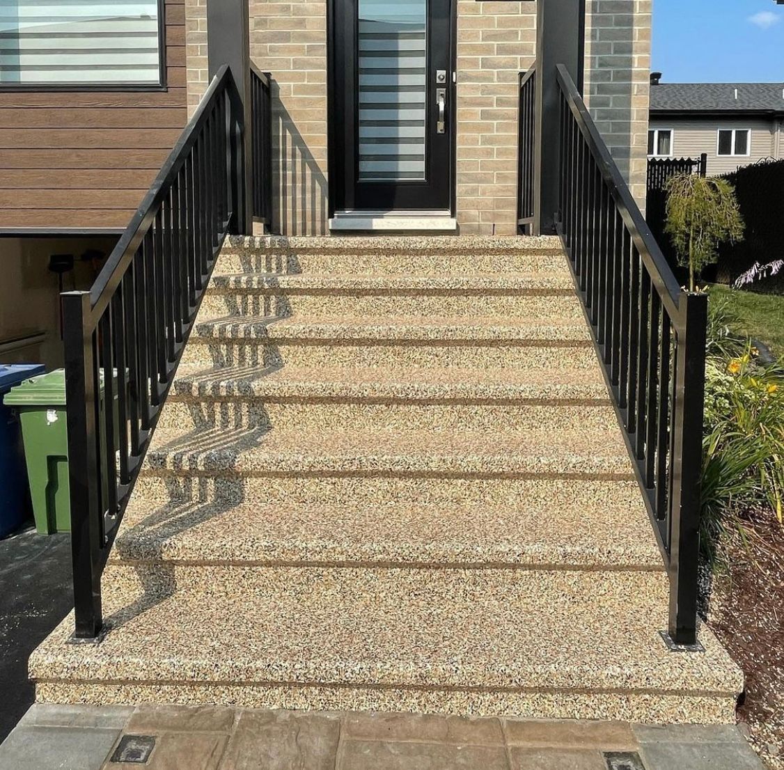 A set of stairs leading up to a house with a black railing.