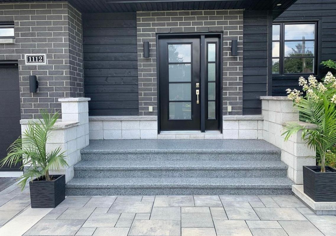 A black brick house with a black door and steps
