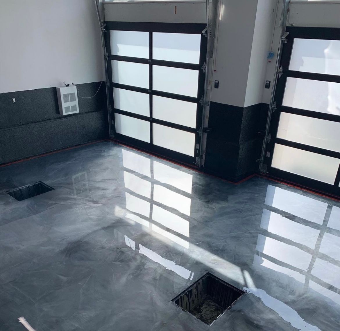 A garage with a gray marble floor and two garage doors.