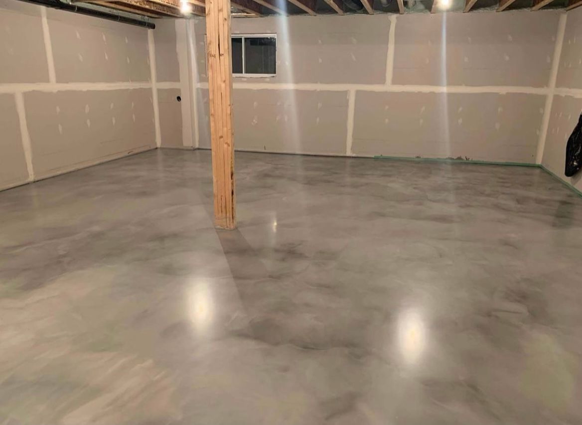 A basement with a concrete floor and a wooden pole.