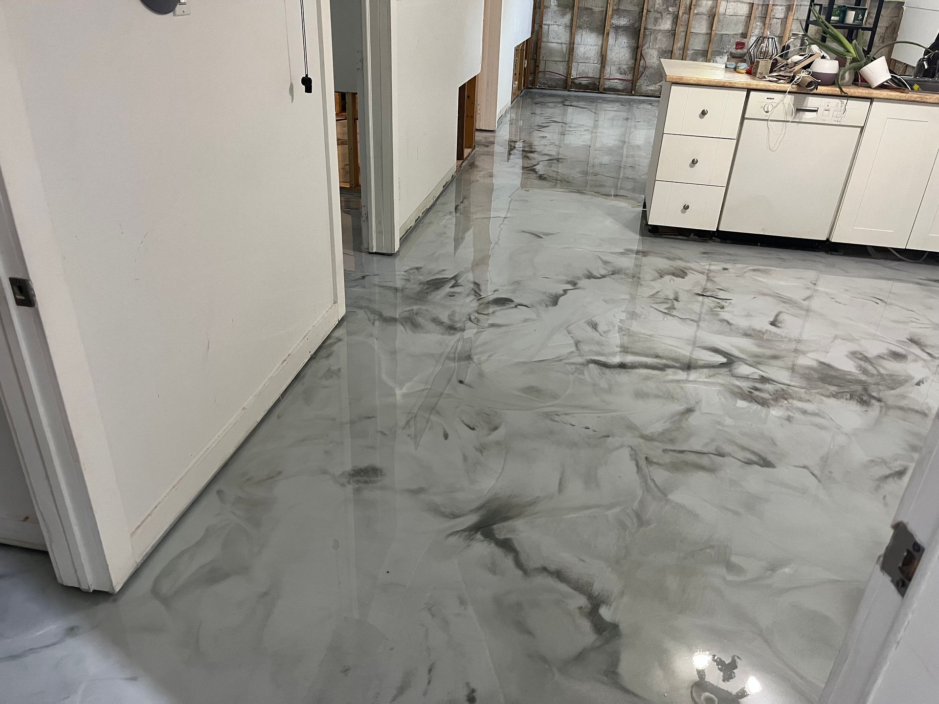 A kitchen with a marble floor and white cabinets.