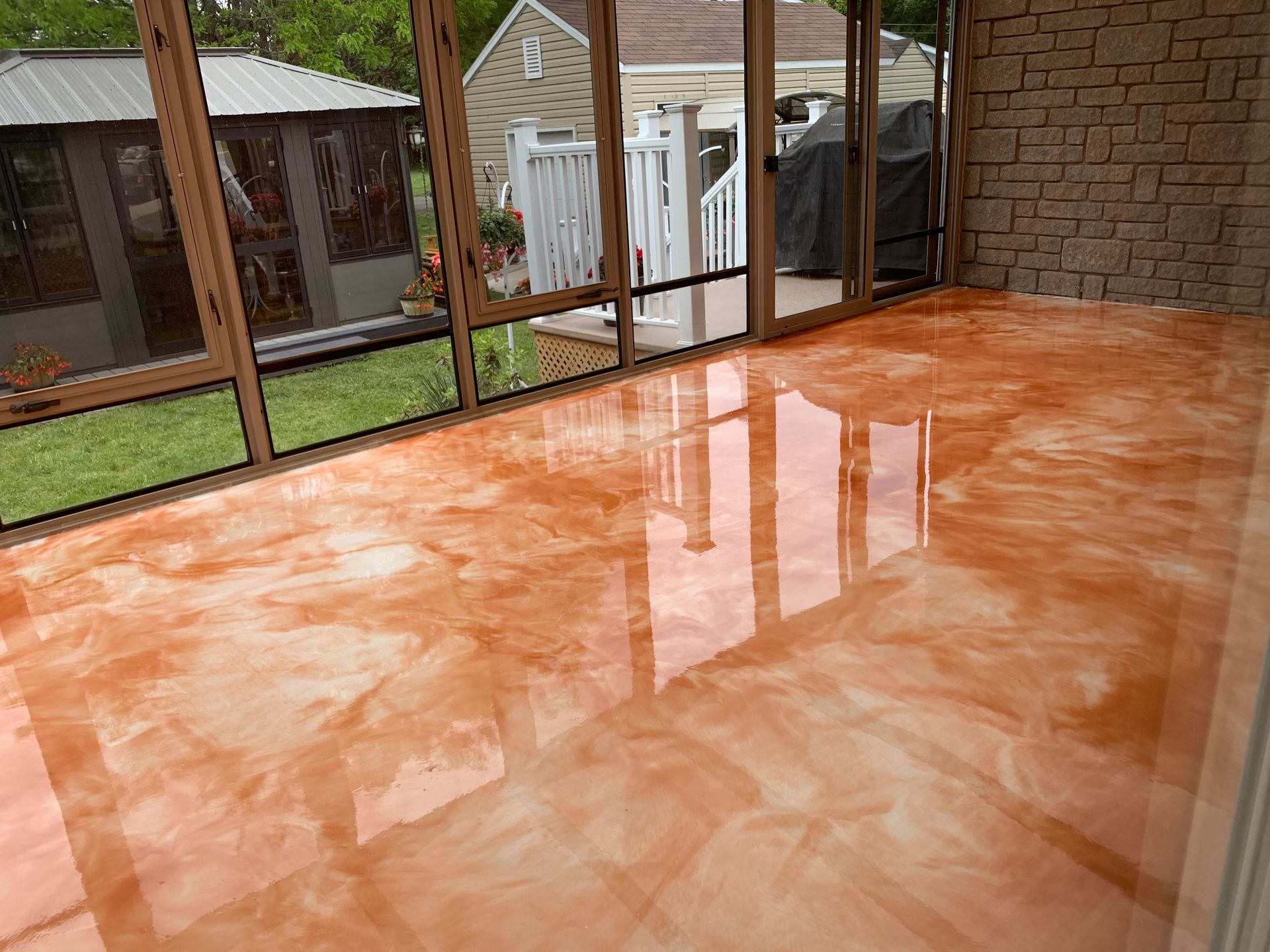 A sun room with a shiny concrete floor and a brick wall.