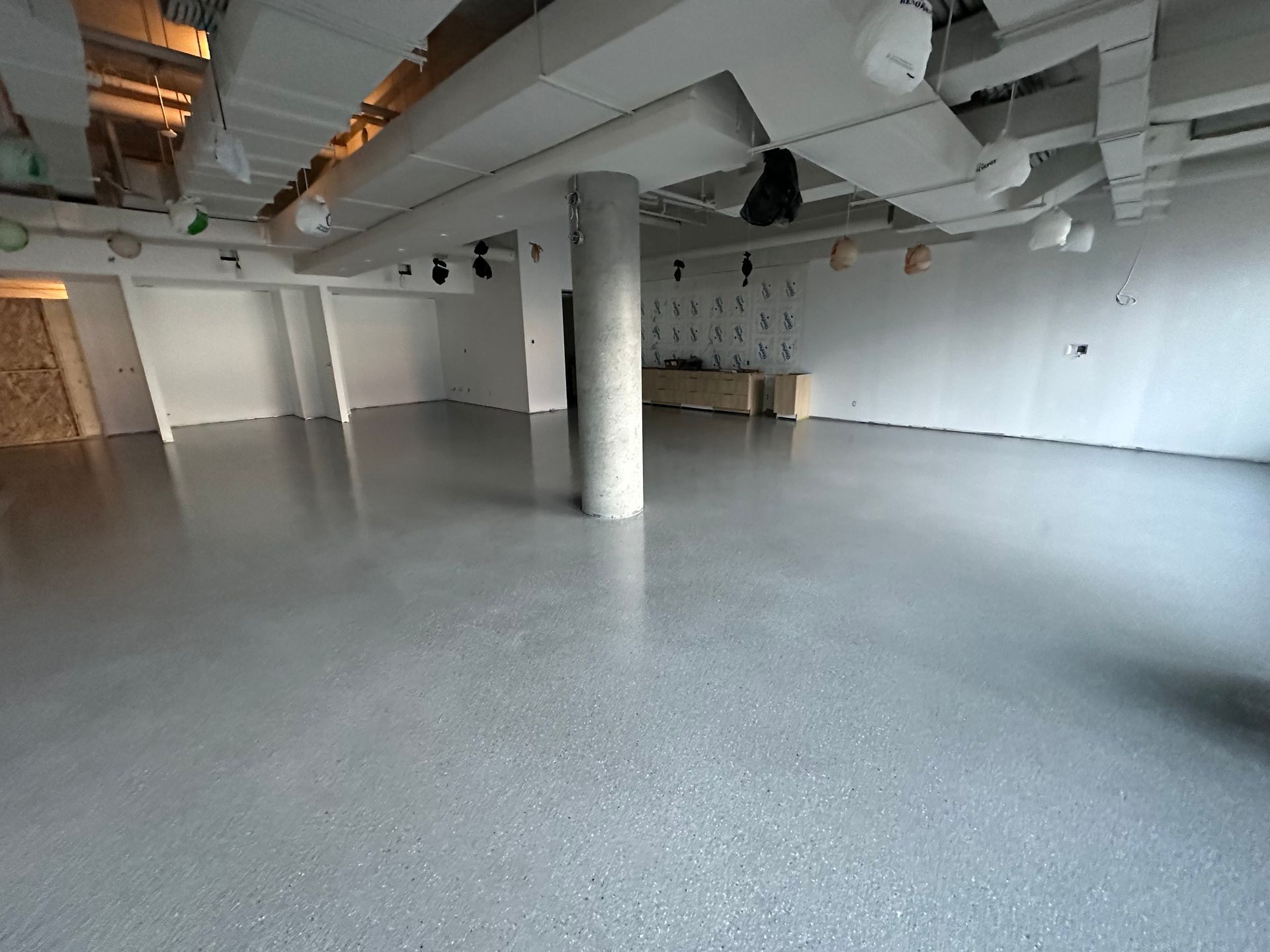 An empty room with a gray floor and white walls