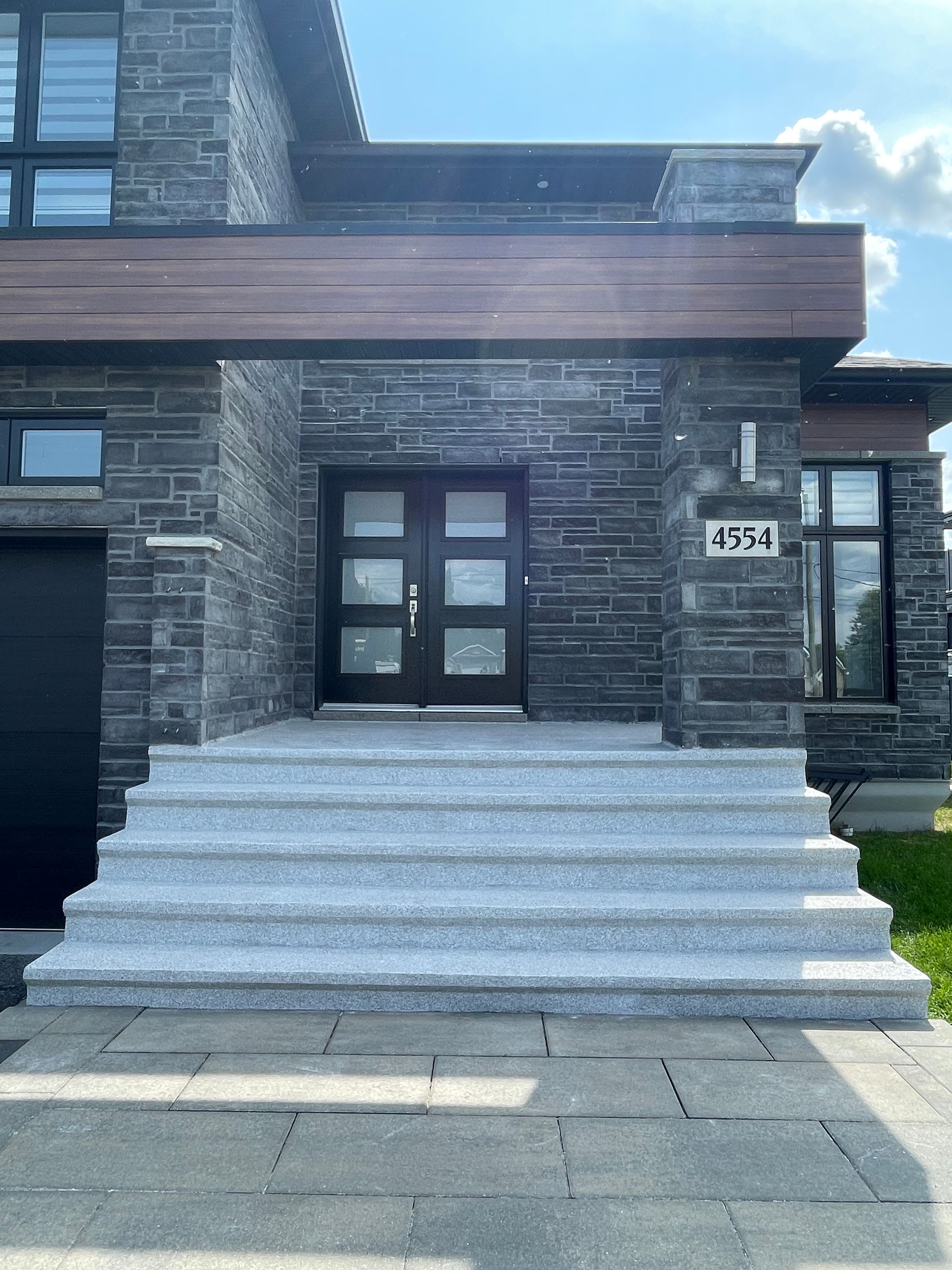 The front of a brick house with stairs leading up to the front door.