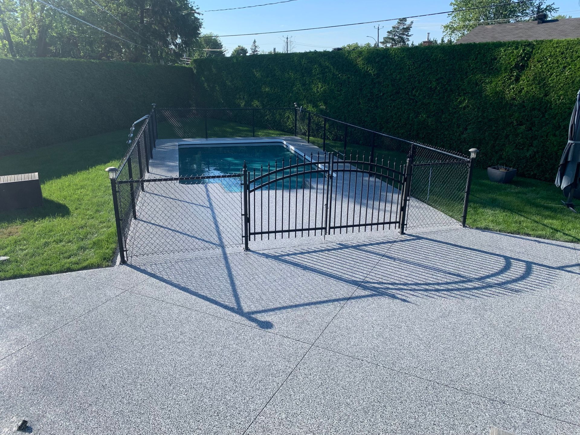 A fence surrounds a swimming pool in a backyard.