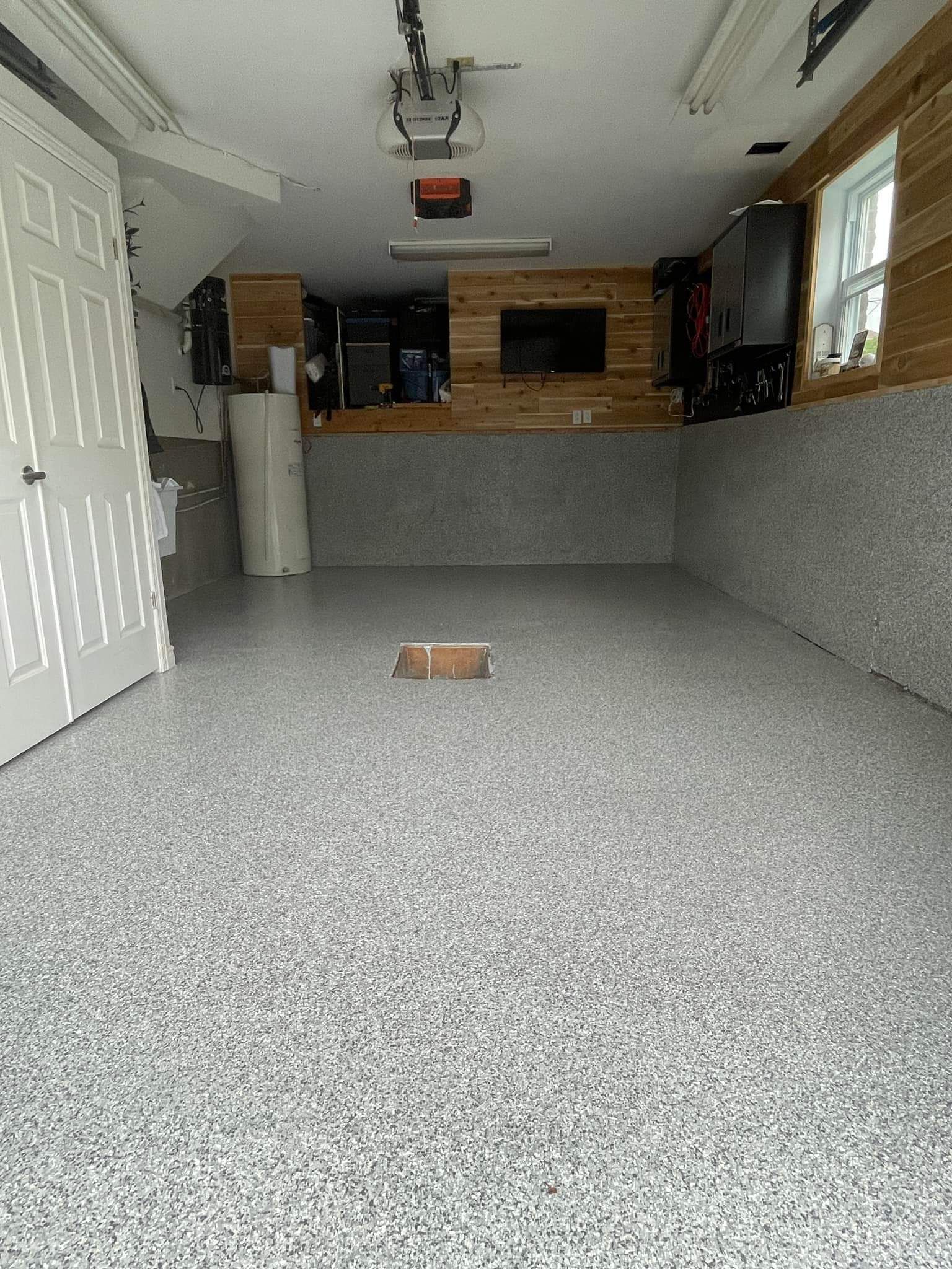 A garage with a gray floor and a hole in the floor.