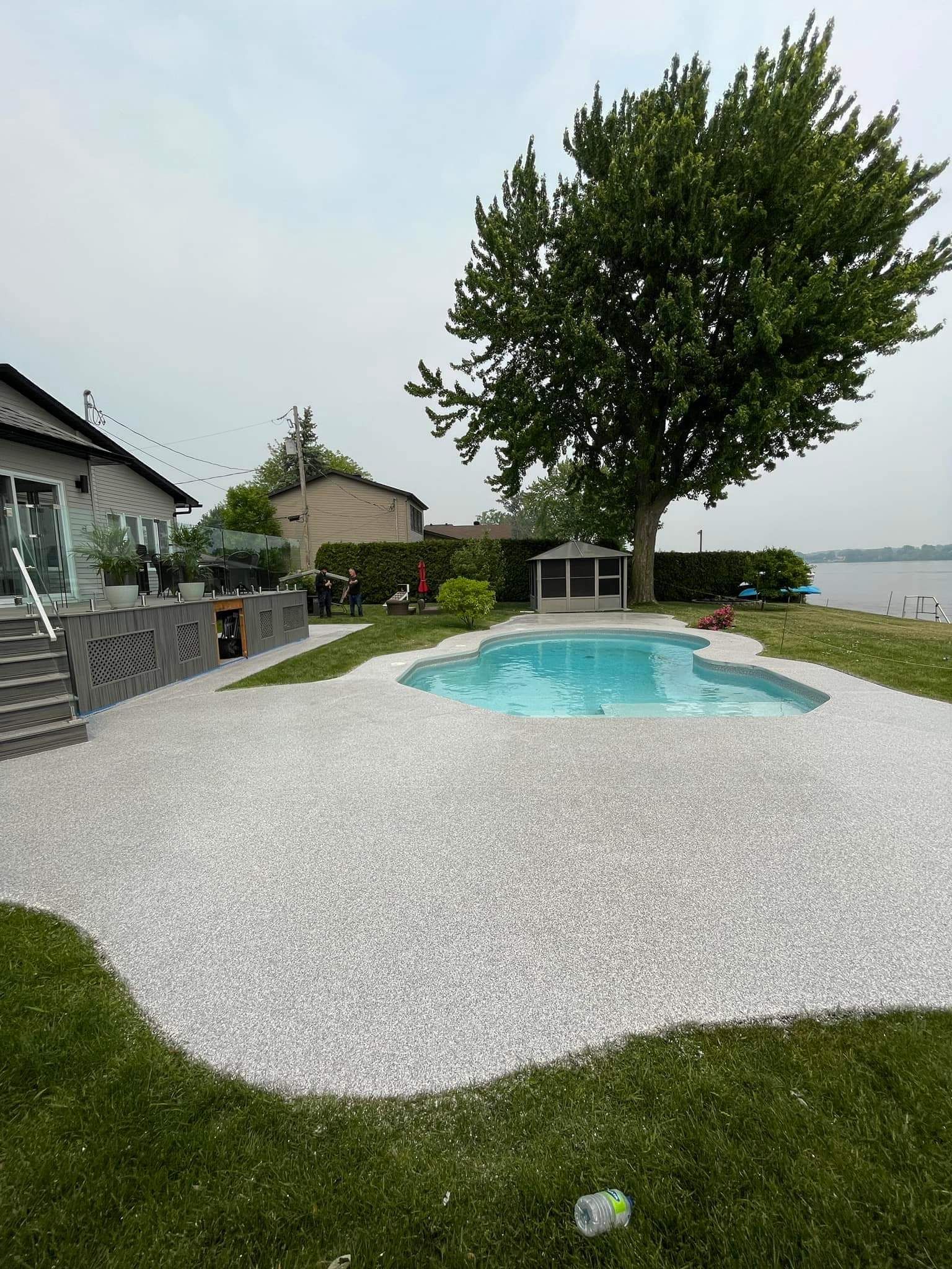 There is a large swimming pool in the backyard of a house.