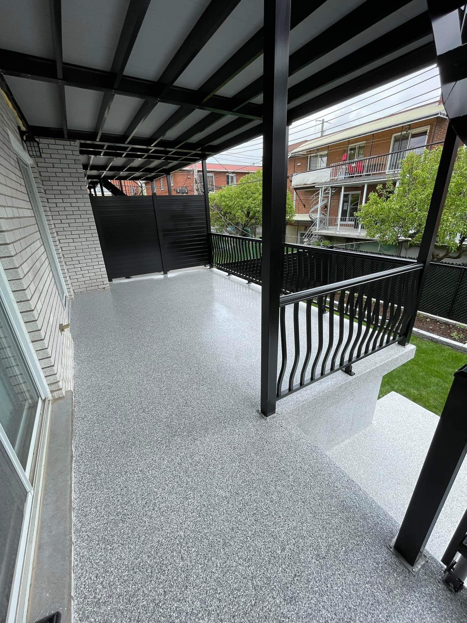 A porch with a concrete floor and a black railing.