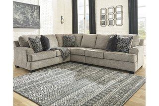 A living room with a sectional couch and a rug.