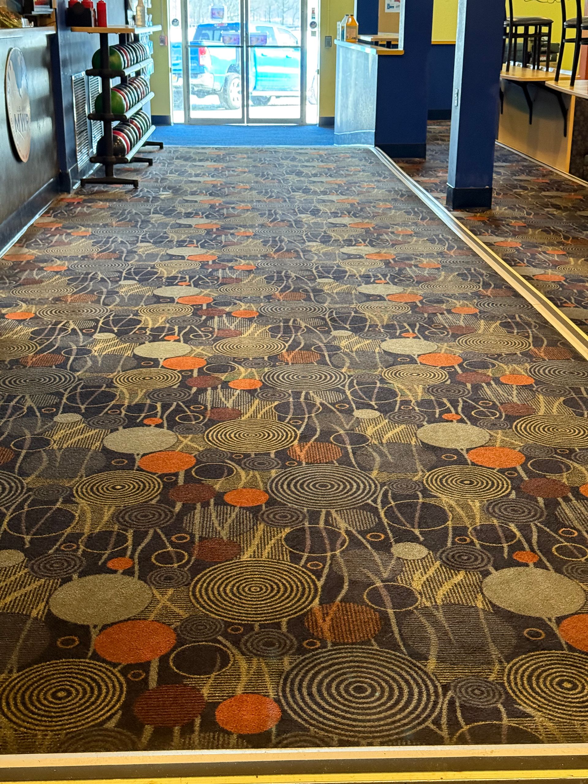 A bowling alley with a colorful carpet and a bowling ball rack.