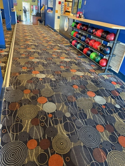 A bowling alley with a colorful carpet and bowling balls