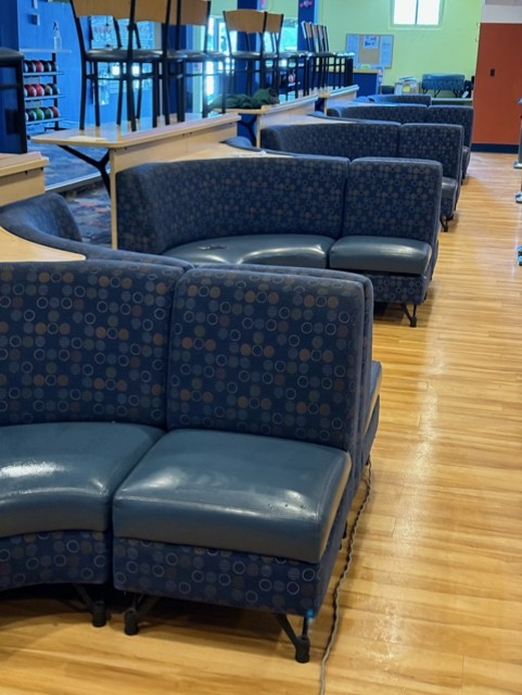 A row of blue couches are lined up on a wooden floor