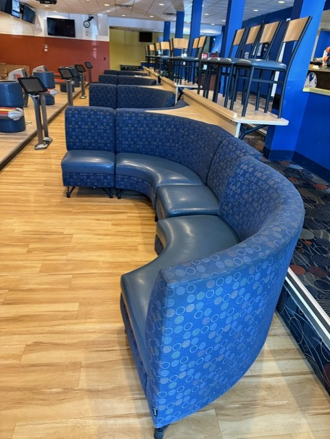 A bowling alley with a curved couch in the middle