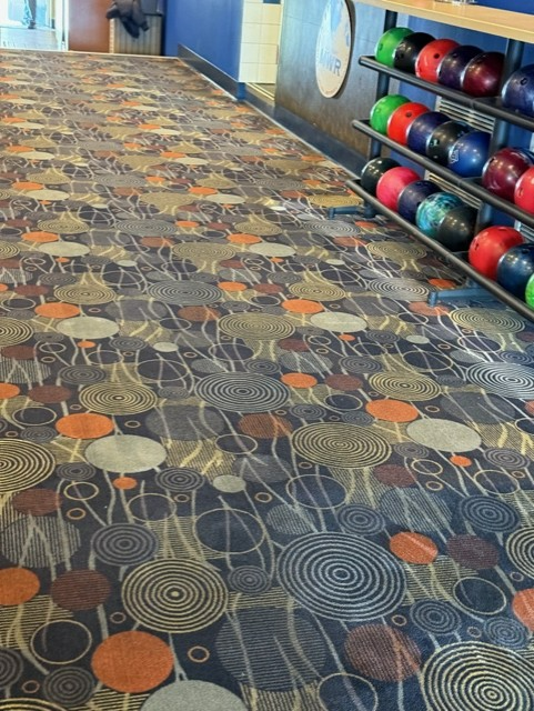 A bowling alley with a colorful carpet and bowling balls