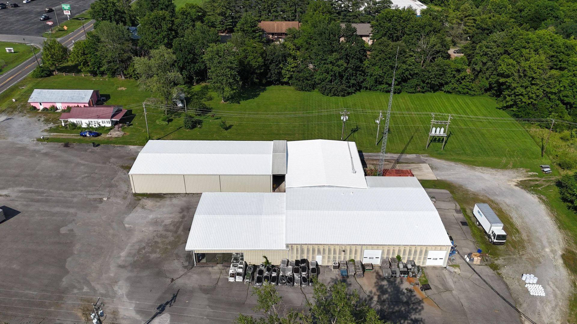 An aerial view of a large building with a white roof surrounded by trees.