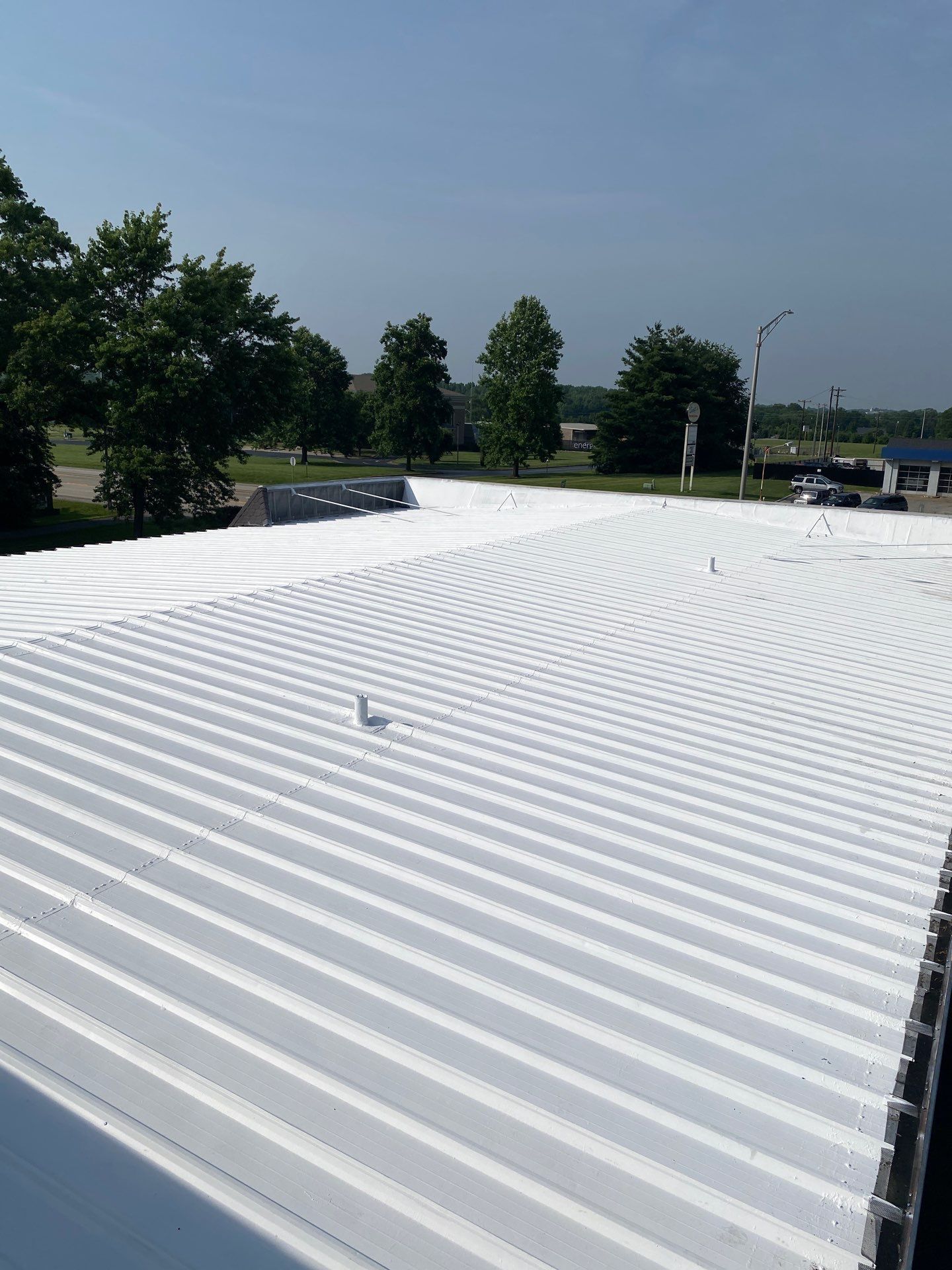 A white roof with trees in the background on a sunny day.