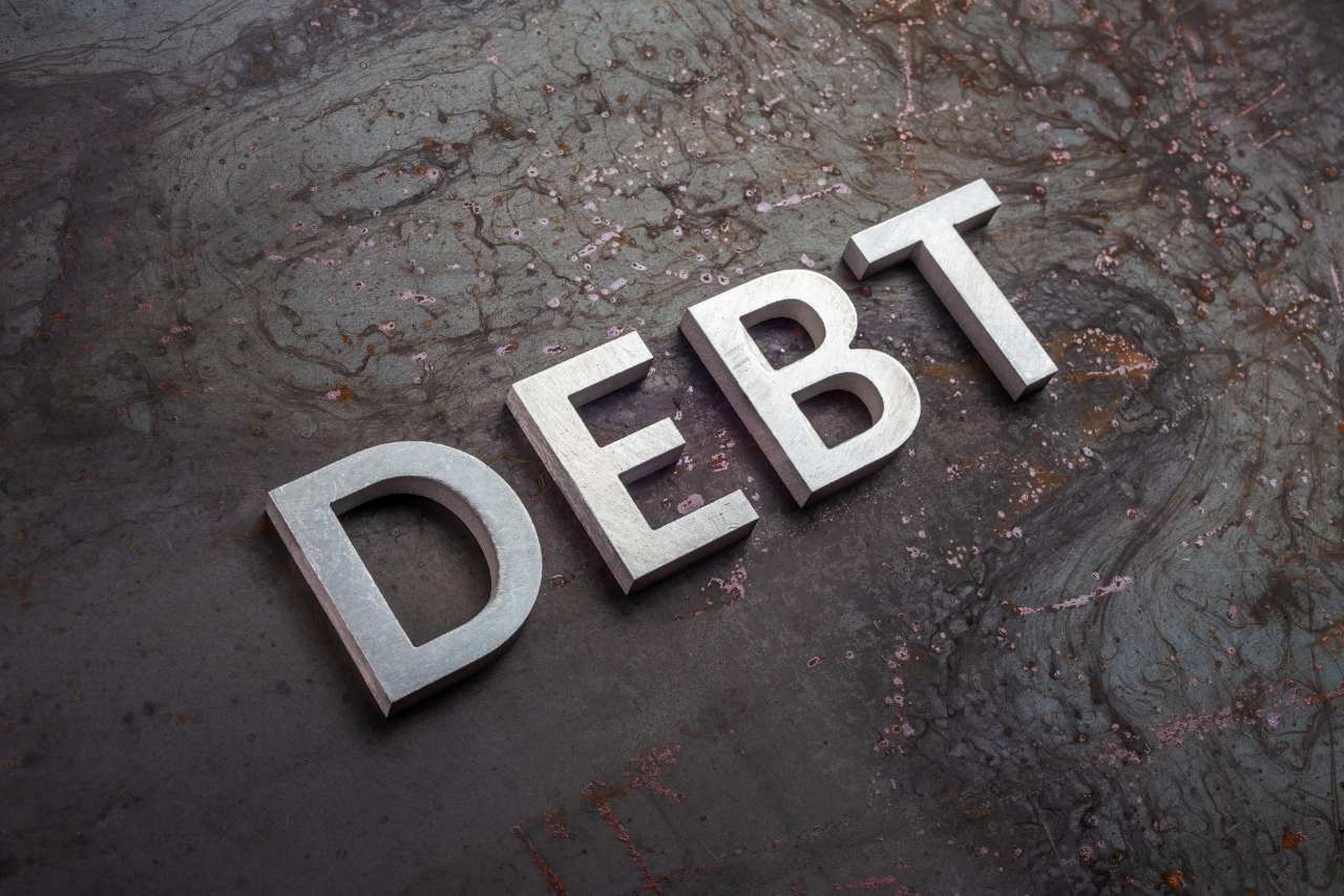 the word debt laid with silver letters on raw rusted steel sheet surface