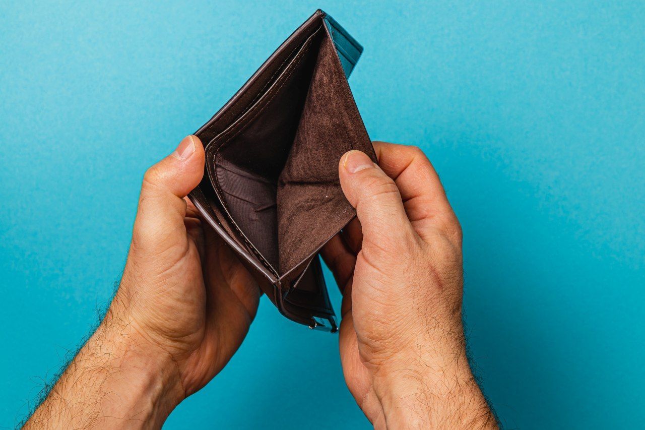 man examines his empty wallet 
