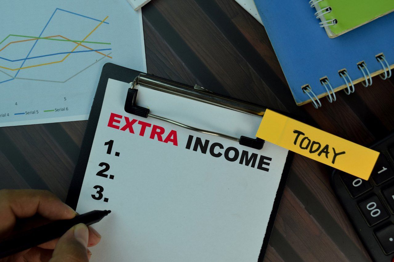 words extra income printed on a paper attached to a clipboard