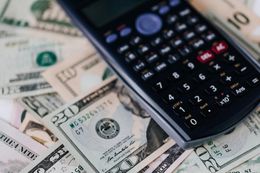 A calculator is sitting on top of a pile of money.