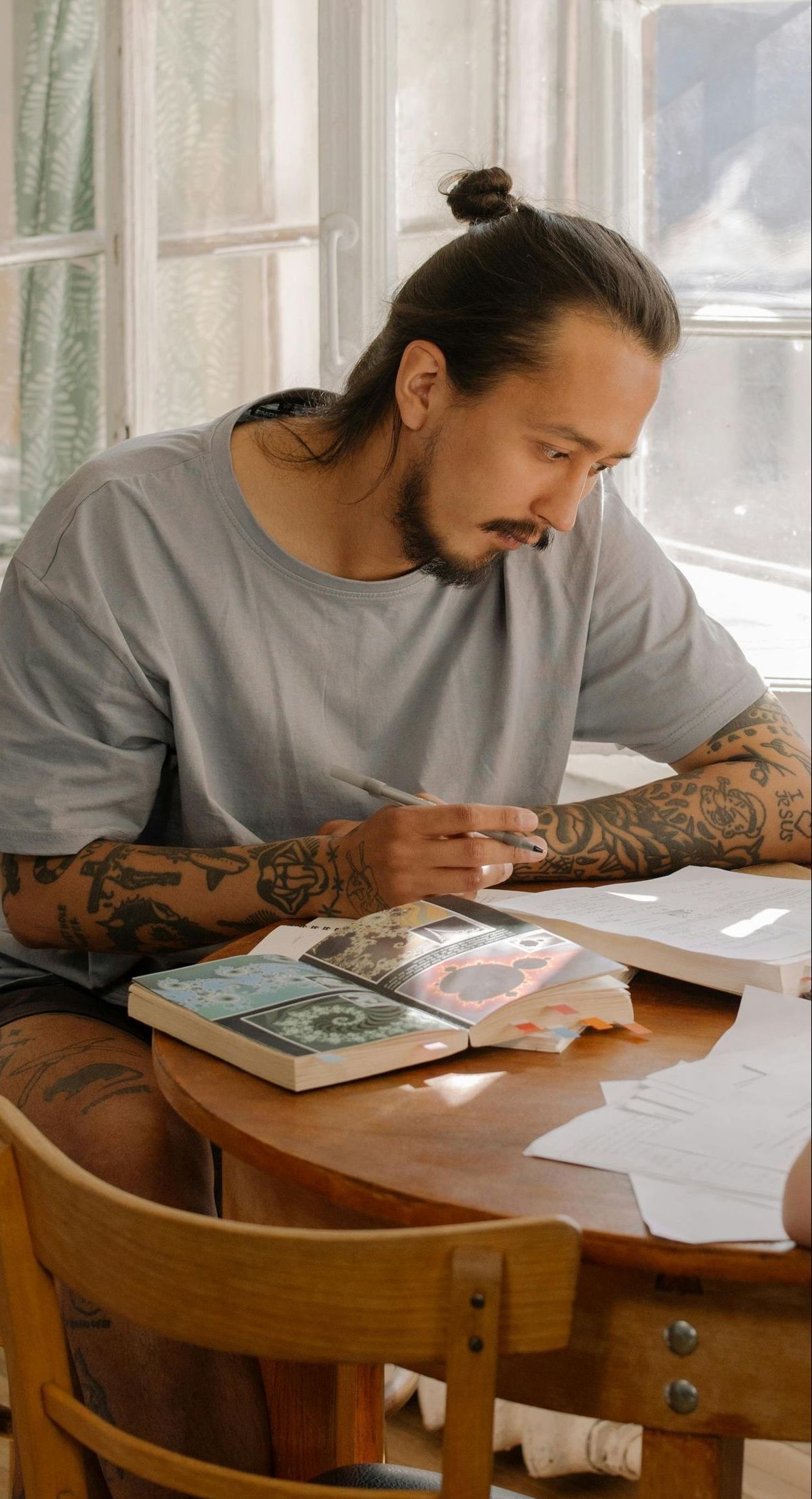 A man is sitting at a table writing in a notebook.