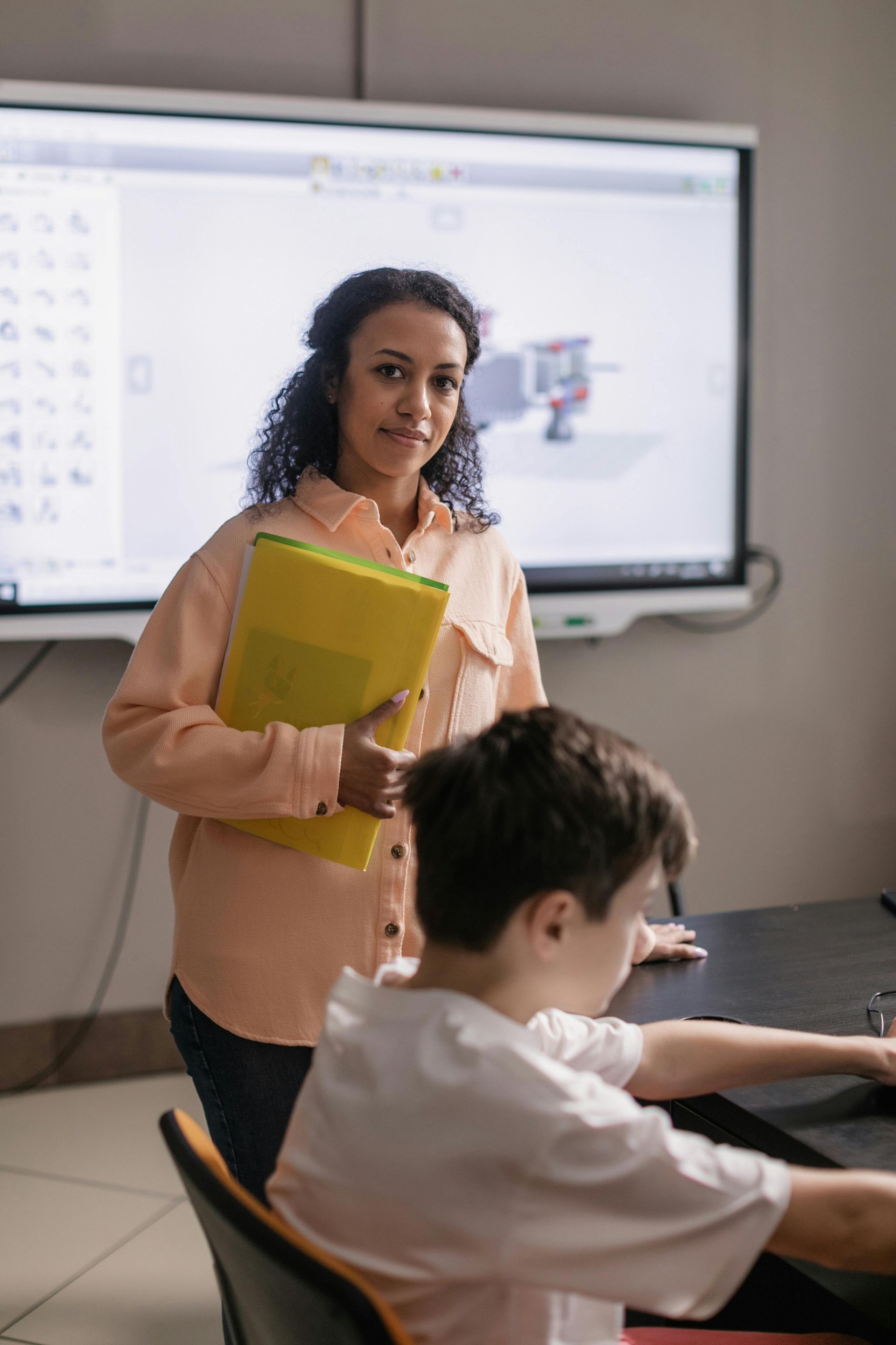 A woman is standing next to a boy in a classroom.